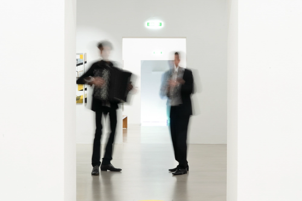 Business Porträt Duo-Klak – künstlerische Bewegungsaufnahme im Museumsflur, beide Musiker verwischt in Bewegung.
