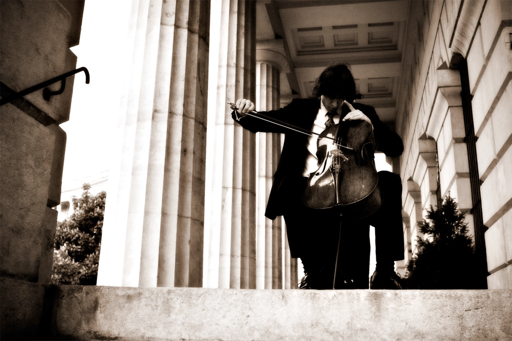 Business Porträt Peter Profant, Profimusiker aus Wien, spielt Cello vor klassischer Säulenarchitektur.