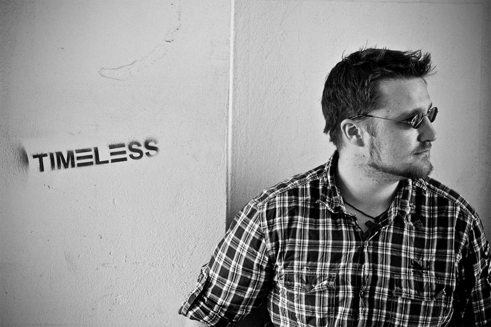 Album Cover Foto Musiker mit E‑Gitarre lehnt an Wand mit »TIMELESS«‑Graffiti in Wien.